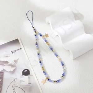 Detail of beaded phone strap with blue crystals and golden star charms on white background