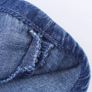 Macro shot of blue denim fabric showing heavy stitching and frayed edge details