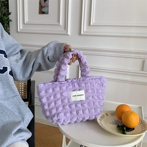 Detail of purple bubble texture canvas handbag with pleated design and brand label