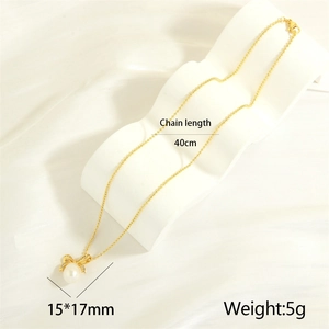 Detailed view of gold bow pendant with white freshwater pearl and sparkling stones