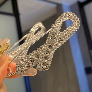 Macro view of large silver safety pin brooch with white crystals for tightening waist