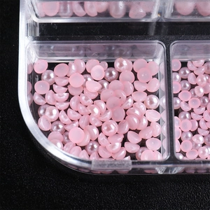 Macro detail of pink half-round aurora pearls in a clear organizer box for nail art