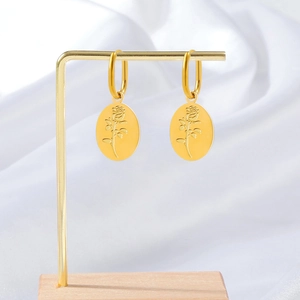 Gold stainless steel rose flower embossed earrings displayed on a wood and metal stand