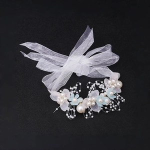 Detail eines Blumen-Haarreifens mit weißen Organza-Bändern und Perlen auf Schwarz