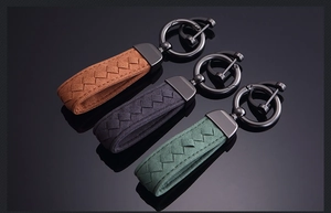 Detail of woven suede leather keychains in brown, gray and green with matte metal hooks