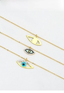Detailed view of three gold titanium steel evil eye pendants with enamel and crystal inlays