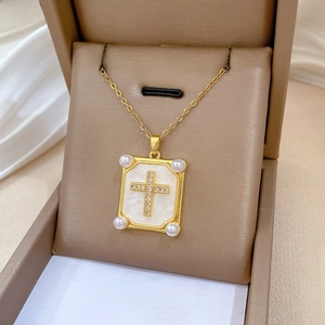 Detail of gold titanium cross pendant with pearls and shell inlay in a gift box