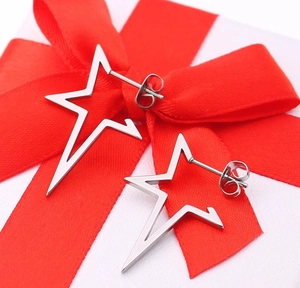 Detail of silver star earrings on white gift box with red ribbon for gifting