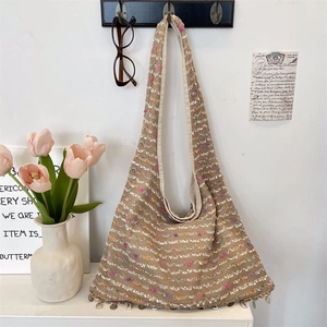 Detailed close-up of bohemian knit tote bag with colorful threads and shell charms