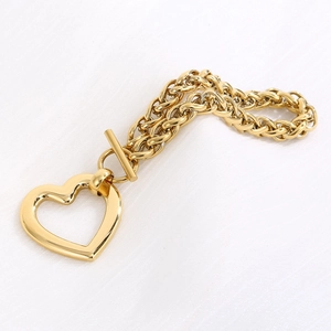 Detailed shot of golden heart pendant bracelet with OT toggle clasp on white fabric