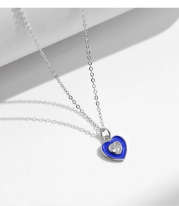 Close-up of heart necklace featuring blue enamel border and clear cubic zirconia center