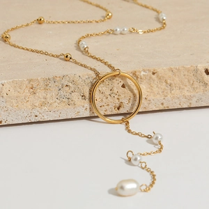 Minimalist gold Y-shaped pearl tassel sweater necklace on a natural stone surface