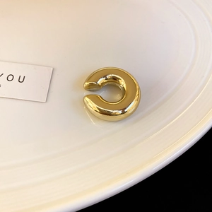 Vue macro d'un ear cuff torsadé doré avec une finition brillante sur assiette