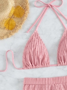 Flat lay of pink ribbed halter bikini with hollow-out details and summer vacation props