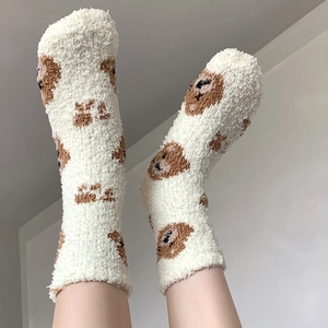 Close-up of white plush coral fleece socks with cute brown bear pattern and soft texture
