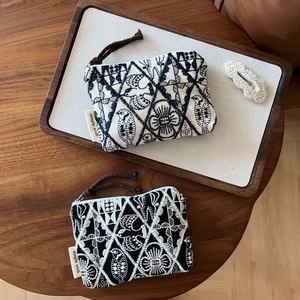 Close-up of bird and floral embroidery on linen coin purses with woven zipper pull