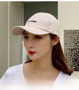 Close-up of a pink cotton baseball cap with a small whale embroidery worn by a model
