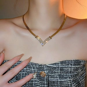 Close-up of a gold-plated V-shaped necklace with crystals on a flat snake chain