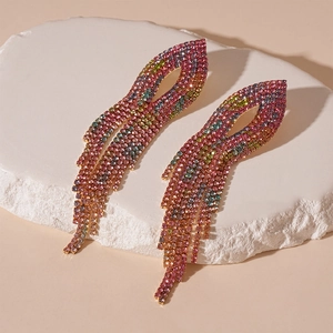 Detailed view of colorful gradient rhinestone tassel earrings on a stone pedestal