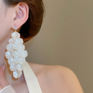 Detail of long layered shell petal tassel earrings with a pearl finish on model