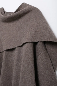 Close-up of brown knit poncho showing refined texture and elegant draped collar design