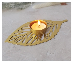 Detail of golden leaf candle holder with filigree patterns on grey marble surface