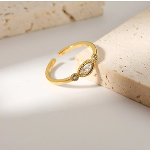 Macro view of adjustable gold-tone ring with marquise-cut stone on natural stone