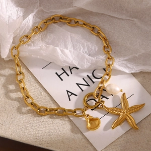 Detail of 18K gold starfish and pearl anklet with textured chain on stylish background