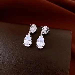 Elegant silver teardrop earrings with clear zircon crystals on dark leather base