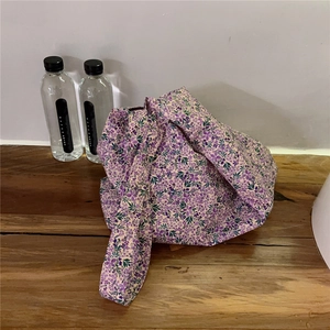 Detail of purple floral cotton knot bag showing fabric texture on a wooden table