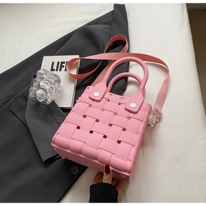 Pink EVA woven texture crossbody bag detail with matching strap and stylish lifestyle props