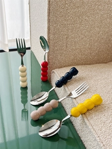 Macro view of stainless steel cutlery with colorful bubble ceramic handles on a table