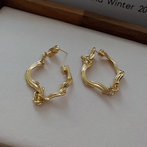 Close-up of golden irregular twisted earrings with glossy metallic finish and texture