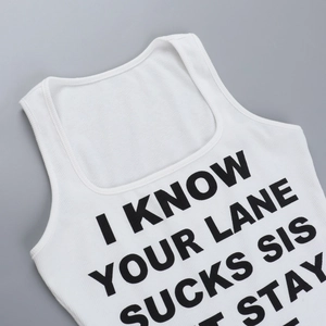 Detail of white rib-knit tank top featuring bold black graphic slogan on the square neck