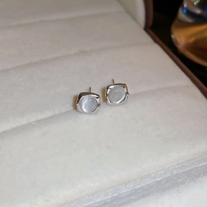 Detail view of silver square stud earrings with white cat eye stone in a jewelry box