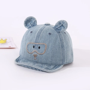 Détail de la casquette bébé en denim avec oreilles d'ours et broderie dessin animé