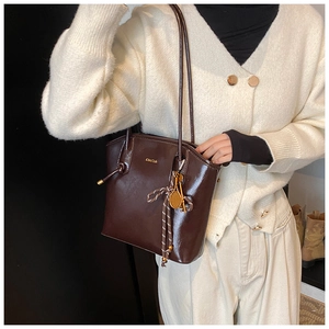 Détail d'un cabas en cuir verni marron foncé avec breloques de clé et raquette de tennis
