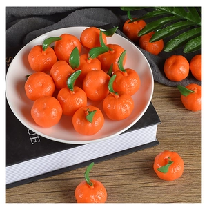 Close-up of realistic PVC mini oranges with green leaves on a white ceramic plate