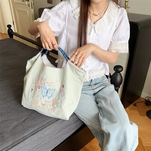 Détail du sac cabas en tissu Oxford vert menthe avec broderie bleue et anses tressées