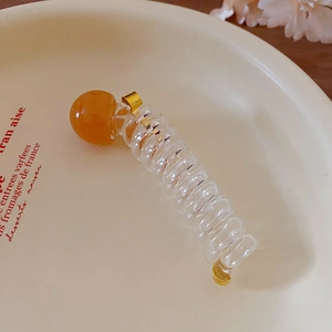 Transparent acrylic spiral hair clip with amber bead detail and gold accents