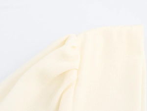 Detail shot of pale yellow soft pleated fabric showing material texture and stitching