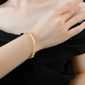 Detail of gold plated brushed metal bracelet with white gemstone accents on wrist
