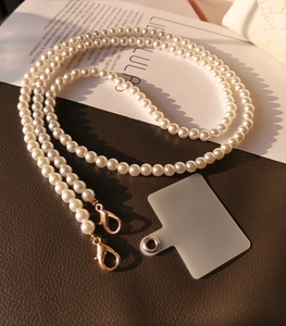 Detail of beaded pearl phone strap with golden lobster clasp and frosted gasket