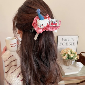 Detail of red gingham hair clip featuring plush cartoon cat mascot on model hair