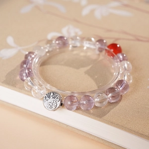 Macro detail of quartz beaded bracelet with Fu character pendant and red agate bead
