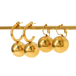 Polished gold hollow ball drop earrings in two minimalist styles on a metal stand