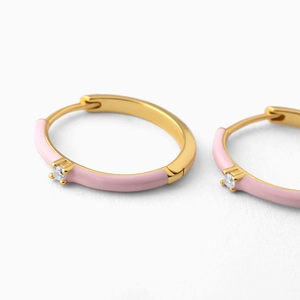 Macro view of gold-plated pink enamel hoop earrings with central sparkling crystal