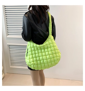 Close-up of neon green quilted cloud bag showing puffed nylon texture and wide strap