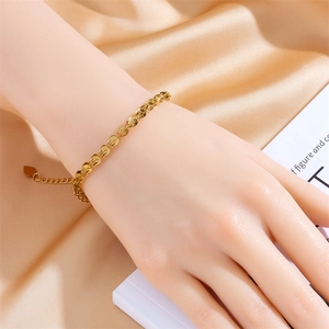 Detailed close-up of golden stainless steel heart chain bracelet on a model's wrist