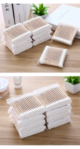 Close-up of double-headed bamboo cotton swabs on a warm wooden surface with natural lighting